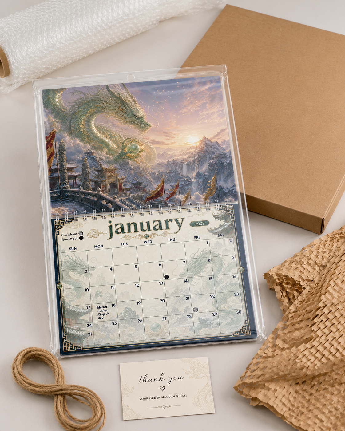 Dragons of China 2027 wall calendar shown wrapped in protective packaging next to its shipping box and thank-you card